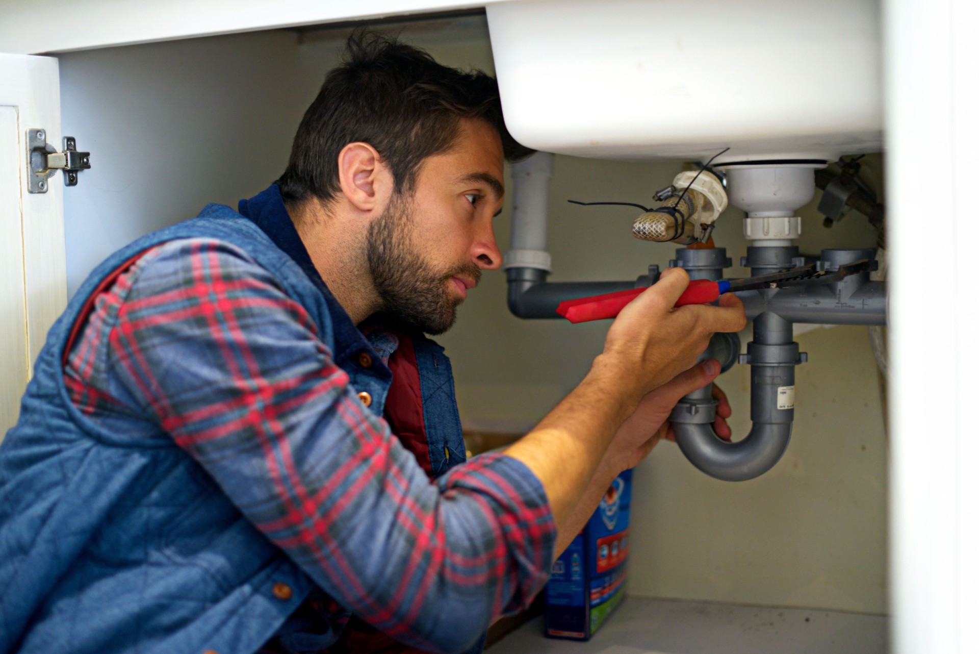 Plumber fixing a sink pipe in a residential bathroom.