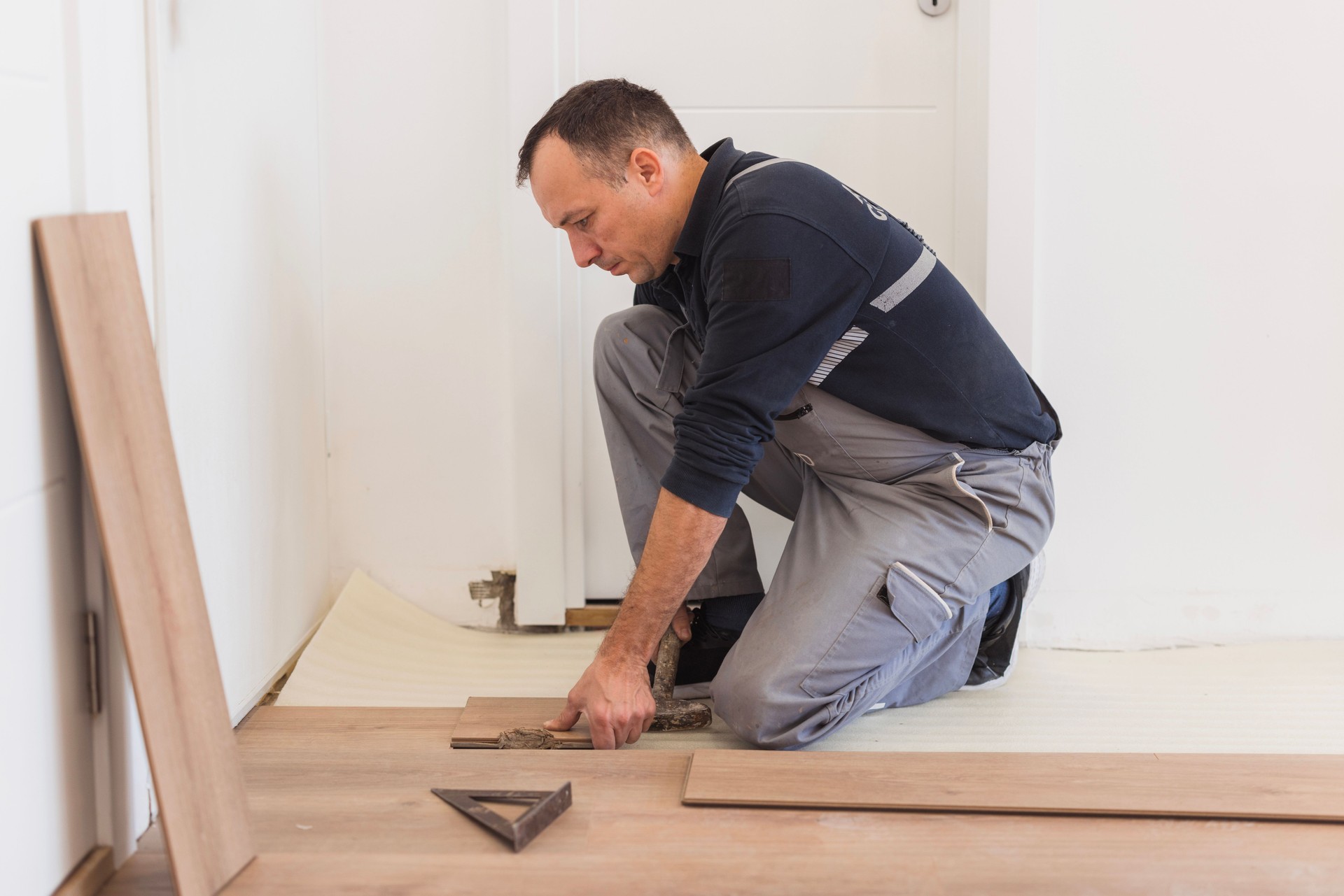 Carpenter laying wooden flooring in a residential home.